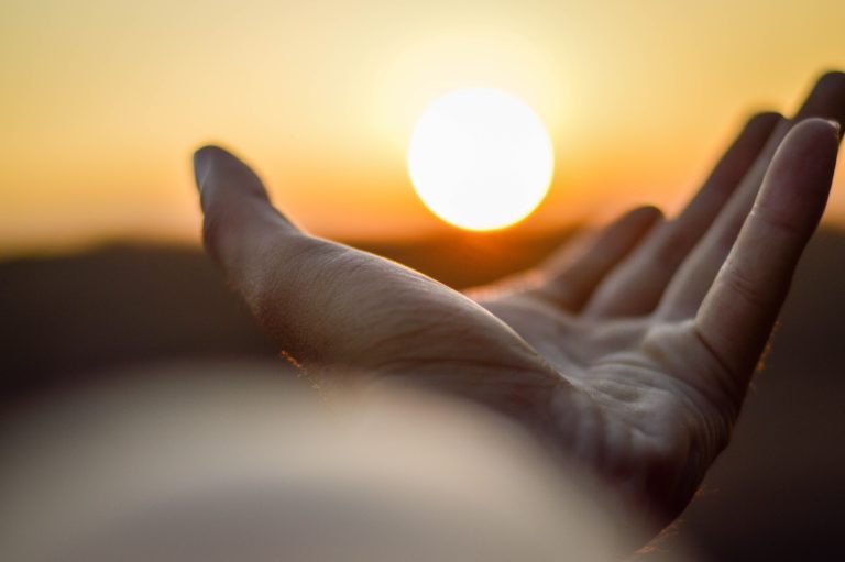 Hand mit Sonne im Hintergrund - Reiki ist Licht-Energie aus den Händen